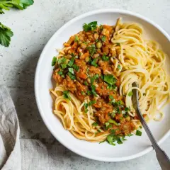 Porcja spaghetti z sosem z soczewicy i warzyw, posypana natką pietruszki. Pyszne i zdrowe spaghetti kcal.