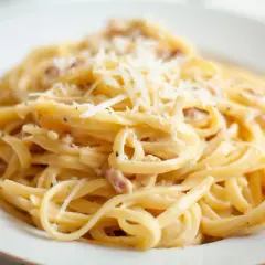 Pyszne spaghetti carbonara, przygotowane według oryginalnego przepisu ze śmietaną, posypane startym parmezanem.