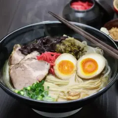 Pyszny ramen: makaron, plastry wieprzowiny, jajko na pół, szczypiorek i marynowane warzywa. Idealny na rozgrzewkę.