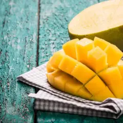 Pokrojone mango na desce. Czy mango ma pestkę? Tak, w środku jest duża pestka, ale to soczyste, żółte mięso jest najsmaczniejsze.