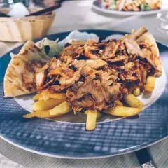 Pyszna shoarma co to? Mięso z kurczaka, frytki i pita na talerzu.