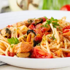 Pyszne spaghetti z owocami morza, pomidorami i świeżą natką pietruszki.