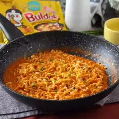 Gorąca, pikantna buldak zupka w sosie, posypana szczypiorkiem, gotowa do jedzenia.