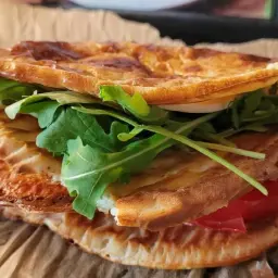Pyszna tortilla z serka wiejskiego z rukolą i pomidorem, idealna na szybki posiłek.