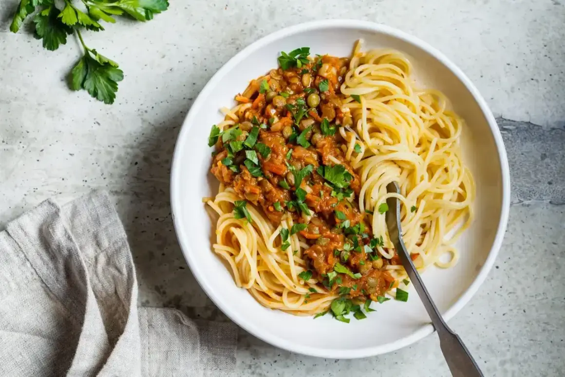 Porcja spaghetti z sosem z soczewicy i warzyw, posypana natką pietruszki. Pyszne i zdrowe spaghetti kcal.