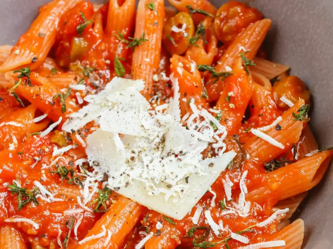 Szybki obiad z makaronem penne w sosie pomidorowym, z oliwkami i parmezanem. Idealny na szybki posiłek.