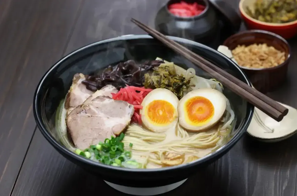Pyszny ramen: makaron, plastry wieprzowiny, jajko na pół, szczypiorek i marynowane warzywa. Idealny na rozgrzewkę.