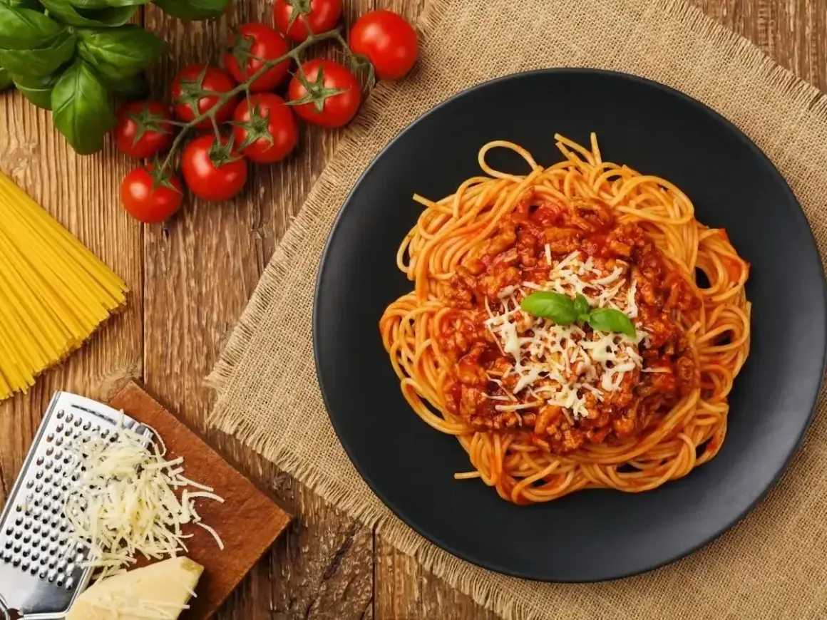 Apetyczne spaghetti bolognese z parmezanem i bazylią. Idealne jakie przyprawy do spaghetti? Zioła, czosnek, pomidory.