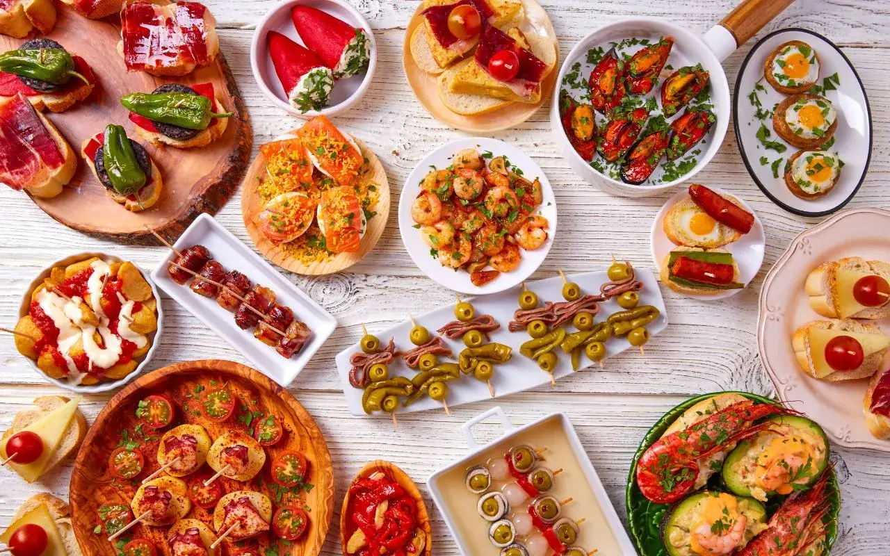 Bogactwo hiszpańskich tapas: krewetki, małże, pieczone papryczki, szaszłyki z boczkiem i oliwkami, kanapki z serem i pomidorkami.