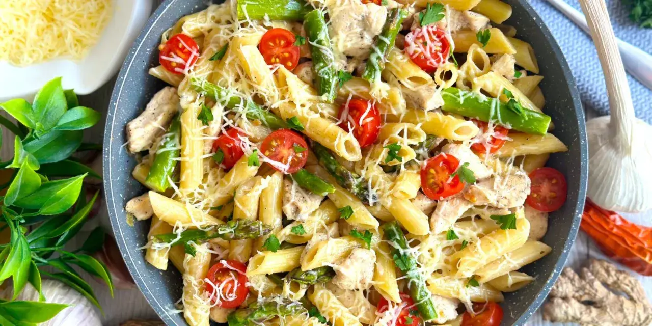 Penne z kurczakiem, szparagami i pomidorkami koktajlowymi, posypane parmezanem. Pyszne danie, które zachwyci każdego.