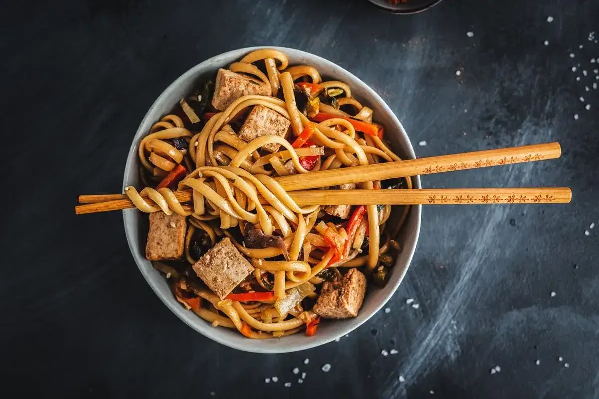 Miseczka pełna makaronu udon z tofu i warzywami, gotowa do jedzenia. Idealny makaron udon przepis na szybki obiad.