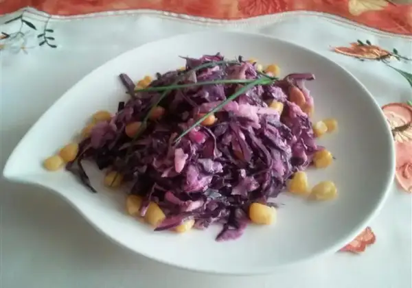 Wykwintna surówka z czerwonej kapusty jak w restauracji, z dodatkiem kukurydzy i szczypiorku, podana na białym talerzu.