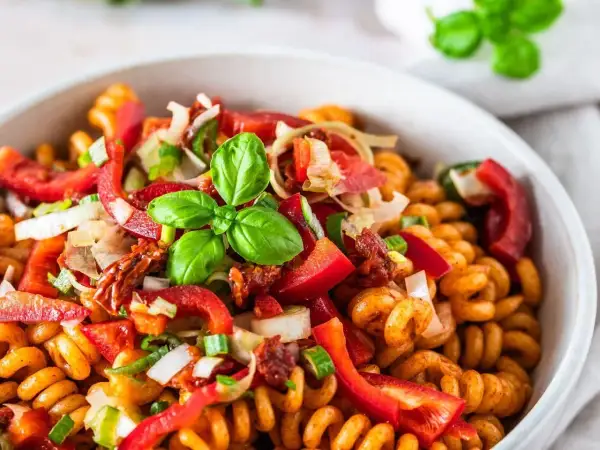 Kolorowa, najlepsza sałatka z makaronem fusilli z papryką, pomidorami suszonymi, cebulą i bazylią.